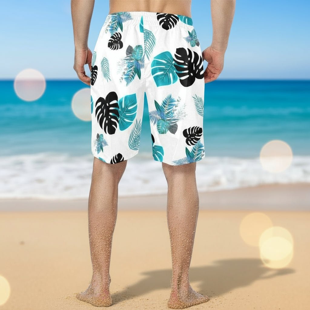 Person wearing white swim shorts with blue and black leaf pattern on a white background