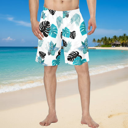 White swim shorts with blue and black leaf pattern worn by a person on a white background